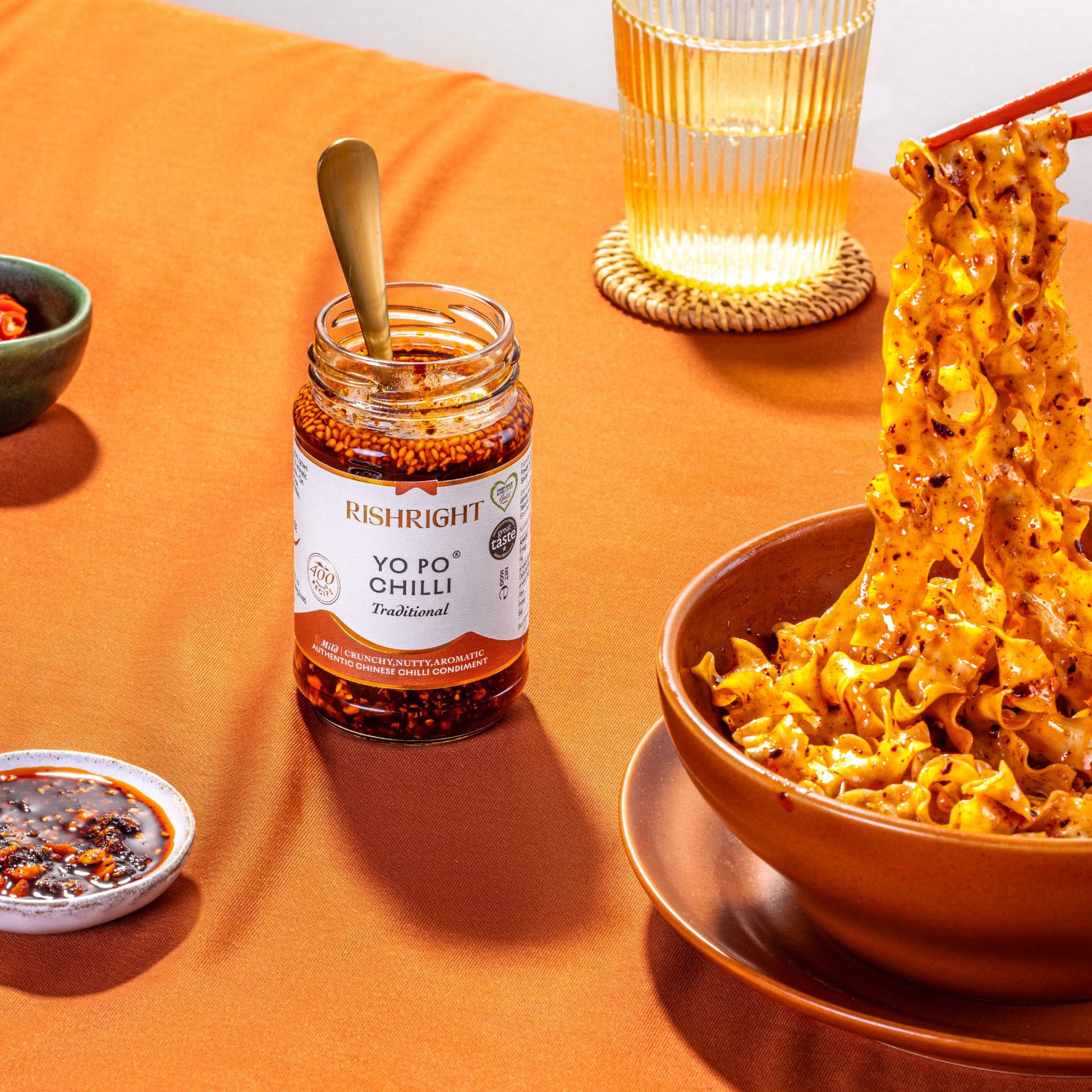 RishRight Yo Po Chilli jar next to noodles drizzled over Crispy Chilli, Nutty Flavour – authentic Chinese chilli oil